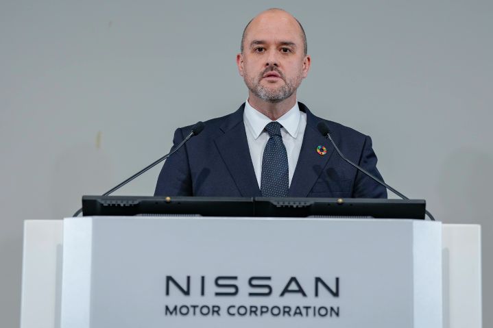 スーツとネクタイを着用し、SDGsのピンバッジを付けた日産自動車CEO イヴァン エスピノーサが、2本のマイクが設置された演台でスピーチを行っている。