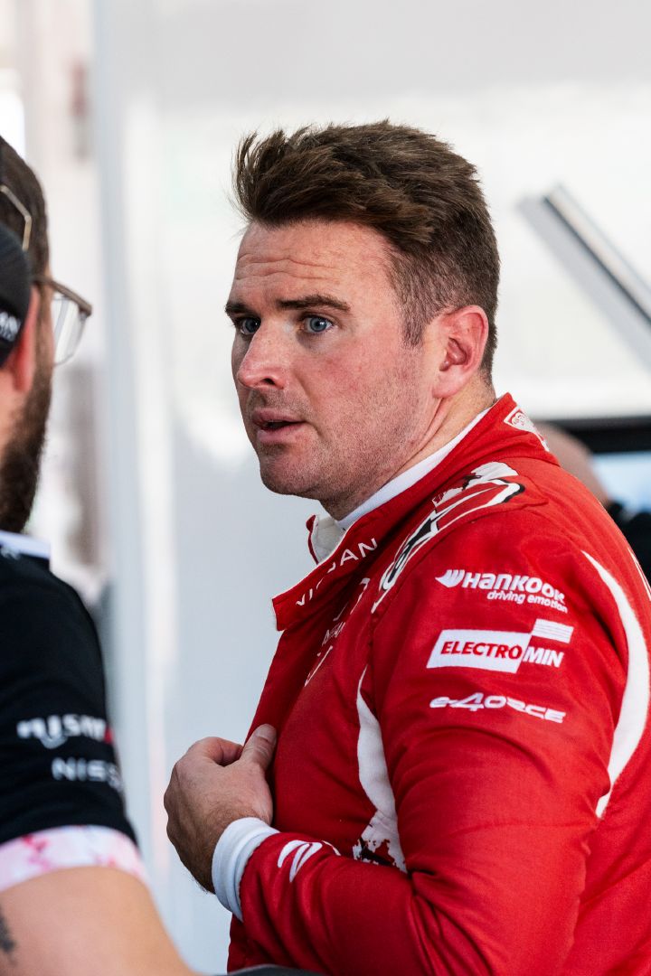 Oliver Rowland in seinem roten Rennanzug im Gespräch mit einem Mitglied des Nissan Teams.