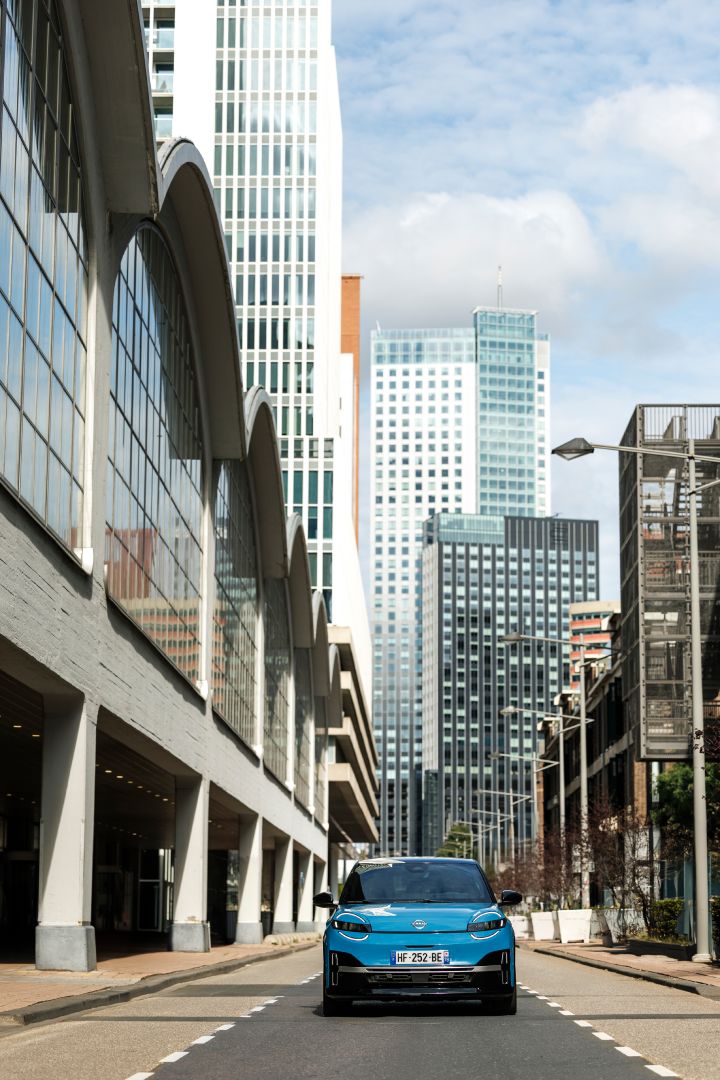 Frontale Ansicht eines blauen Nissan Micra auf einer Straße zwischen Hochhäusern in Rotterdam