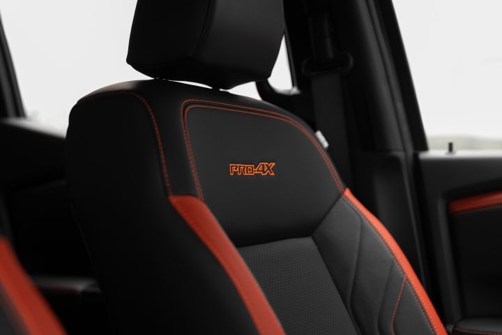 2026 Nissan Navara PRO-4X finished in Boulder Grey depicting the front passenger seat with embroidered backrest, perforated centre panel and contrasting red bolsters.