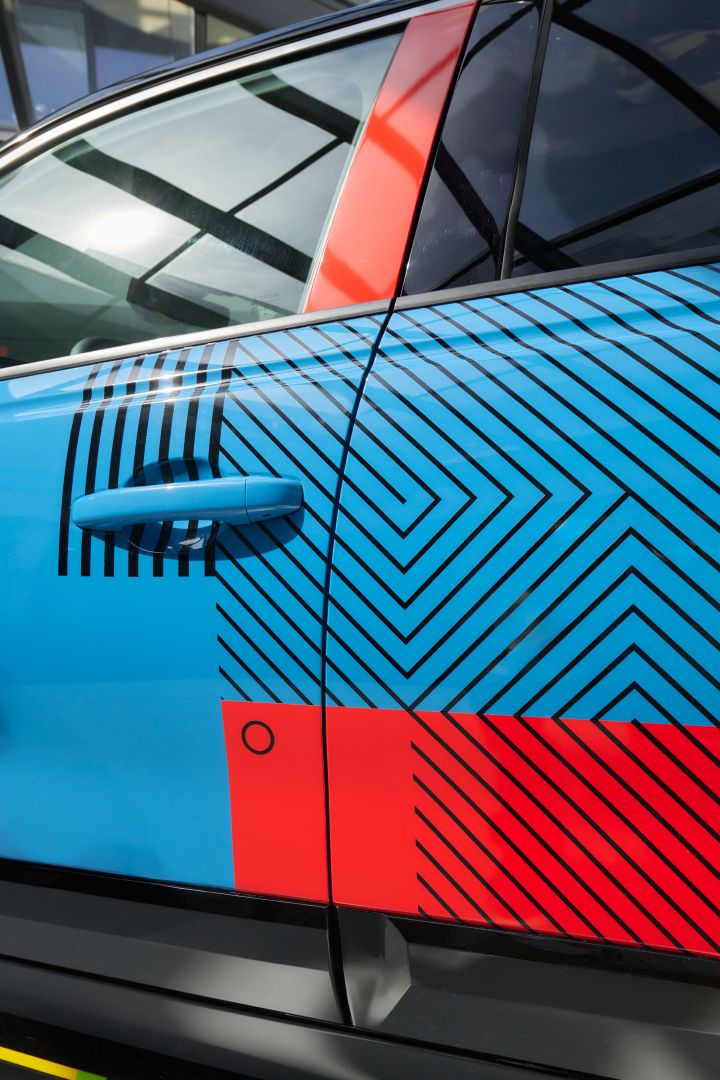 Detailaufnahme des Nissan Micra Signature Edition Gewinnerfahrzeugs mit rot-schwarzer B-Säule und grafischen Mustern auf den blau lackierten Türen