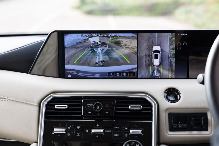 2026 Nissan Y63 Patrol finished in white, interior close-up showing the infotainment display with rear-view and overhead camera views of a boat trailer during towing manoeuvres.
