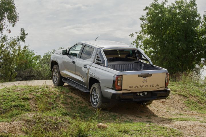 2026 Nissan Navara ST dual cab ute finished in Summit Silver shown from the front three-quarter angle descending a dirt slope.