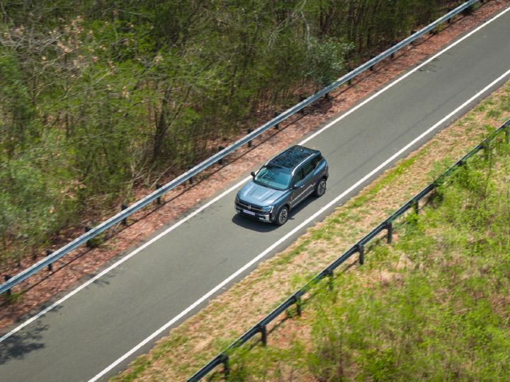 Overhead view of the Nissan Tekton driving on a tree-lined roadway.