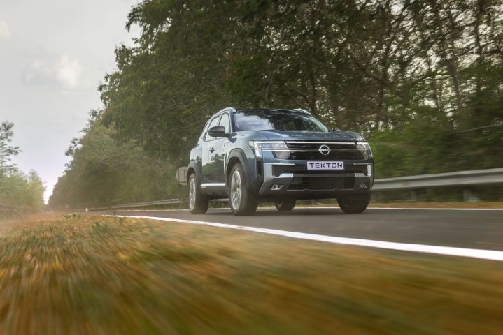Low-angle tracking shot of the Nissan Tekton travelling along a rural roadway.
