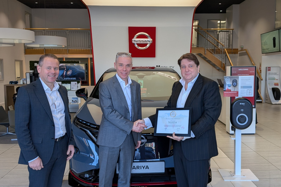 Three people stand in a car dealership holding a certificate showing their new Pride365 certification
