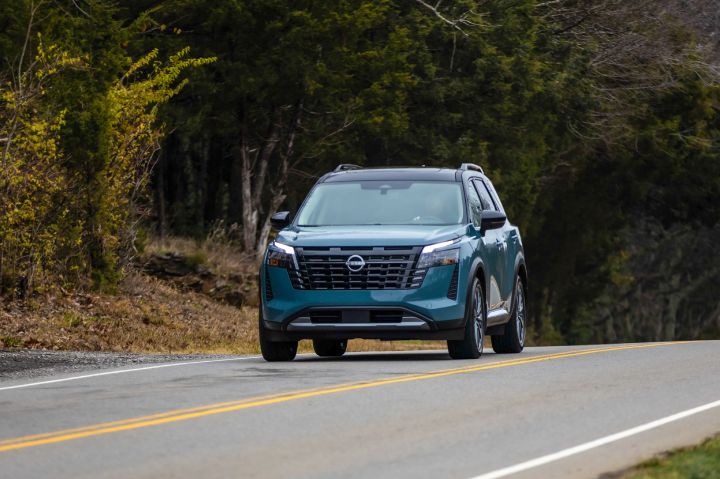 Front view of the 2026 Nissan Pathfinder driving along a tree-lined road.