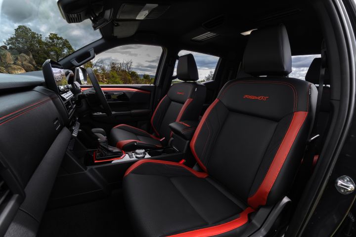 2026 Nissan Navara PRO-4X finished in Boulder Grey showing the front-seat interior with red inserts, PRO-4X embroidery and centre console.