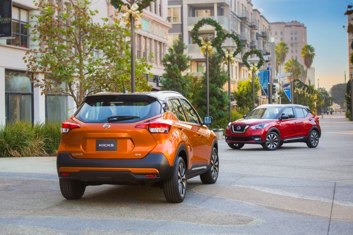 Deux SUV Nissan Kicks garés dans une rue de la ville avec des palmiers et des bâtiments en toile de fond.