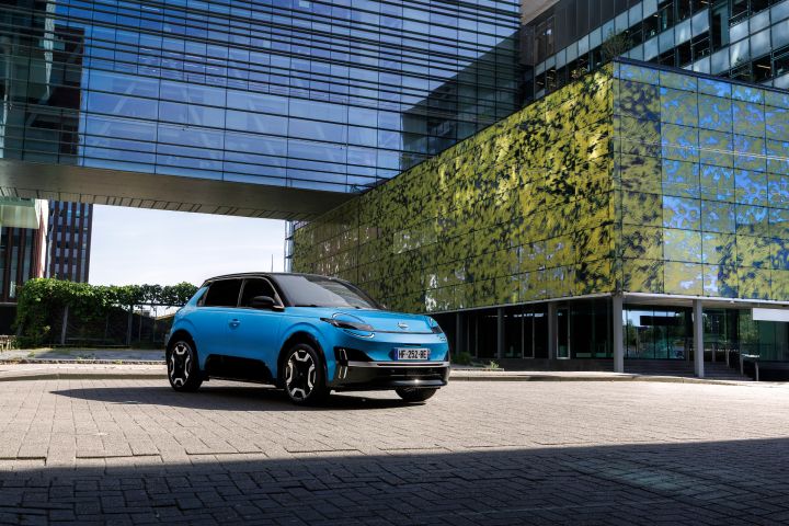Blick von schräg vorne auf einen blauen Nissan Micra, der vor einem begrünten Gebäude in Rotterdam steht.
