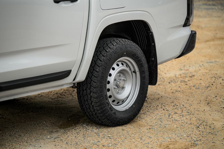 2026 Nissan Navara SL dual cab ute finished in Alpine White captured at the rear wheel area, featuring the steel rim, tyre pattern, mudflap and rear bumper edge