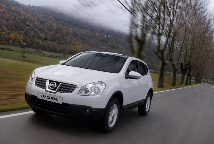 A second generation Qashqai driving past a set of trees