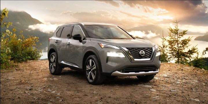 Grey Nissan Rogue sitting atop a mountain