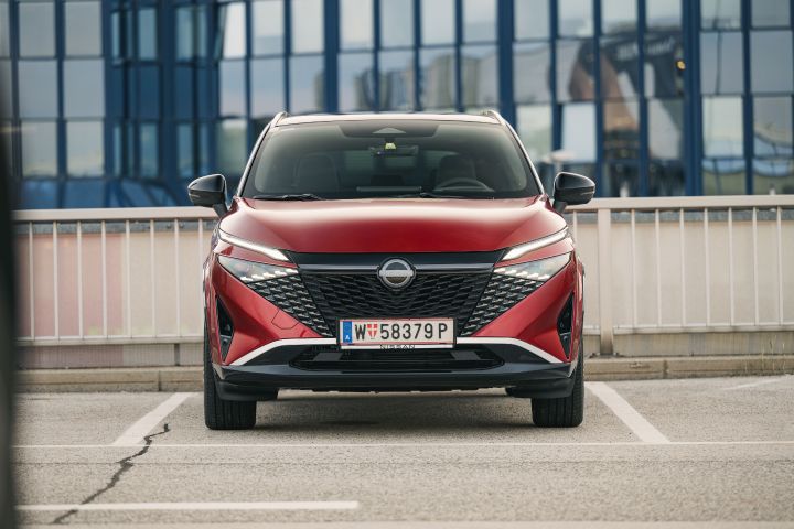 Frontansicht eines stehenden Nissan Qashqai in Fuji Sunset Red auf einem Parkplatz