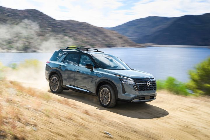 Front right 3/4 view of the 2026 Nissan Pathfinder driving along a dirt path with a dust cloud trailing behind.