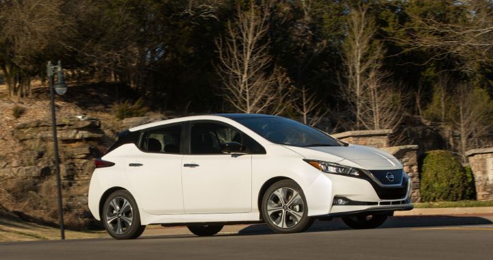 A white Nissan LEAF driving on a road