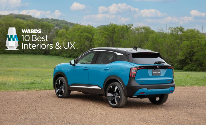 Left rear 3/4 view of a blue 2025 Nissan Kicks parked on gravel near grass. An award logo is in the top left.