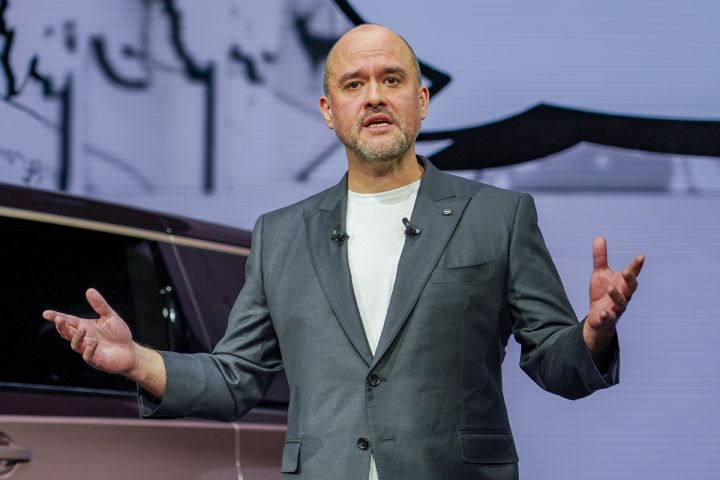 On stage, CEO Ivan Espinosa stands in a suit, gesturing with both hands while delivering a presentation. The background features a white screen with simple line art.