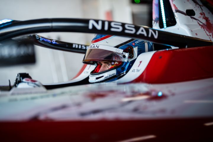 Seitenaufnahme von Oliver Rowland mit aufgesetztem Helm und hochgeklapptem Visier, wie er in der Teamgarage sitzt, bevor er auf die Strecke geht.