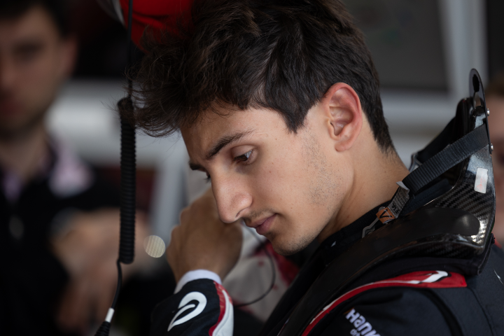 Gabriele Minì preparing himself for the session with his HANS device attached and putting in his earpieces into his right ear (not visible).