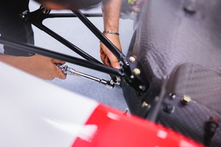 Nahaufnahme von zwei Händen mit Werkzeug am Nissan Formel E Rennboliden
