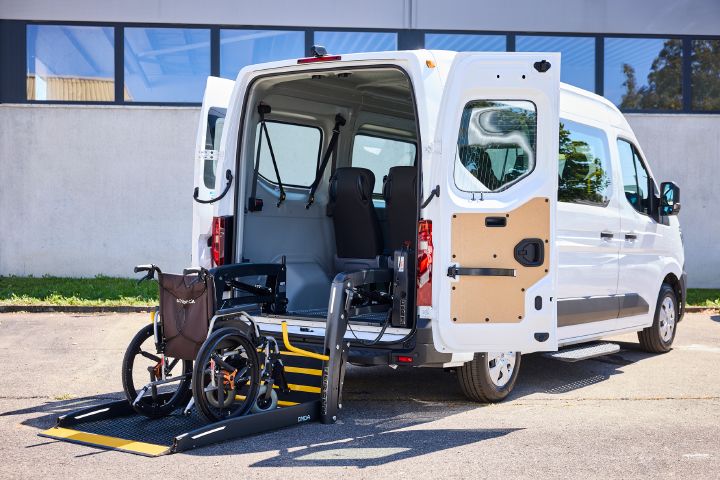 3/4 Heckansicht eines weißen Nissan Interstar-e mit MobiTEC Ausbau, an dessen Heck der Rollstuhllift auf Straßenniveau heruntergelassen wurde, ein Rollstuhl steht auf dem Lift