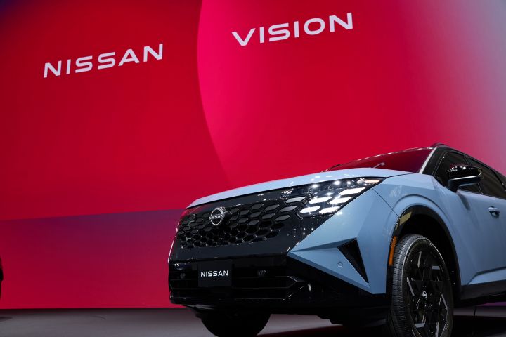 angled front view of the 2027 Nissan Rogue Hybrid e‑POWER on a stage with a screen that reads "Nissan Vision."