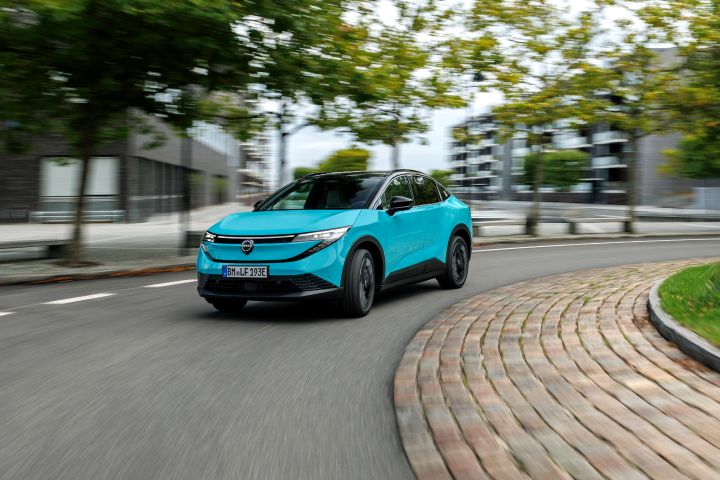 Ein türkiser Nissan LEAF biegt zügig um eine Linkskurve im städtischen Umfeld von Kopenhagen