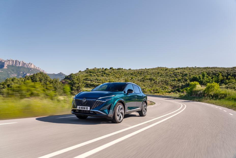 Nowy Nissan Qashqai e‑POWER w kolorze butelkowej zieleni na górskiej drodze w słoneczny dzień