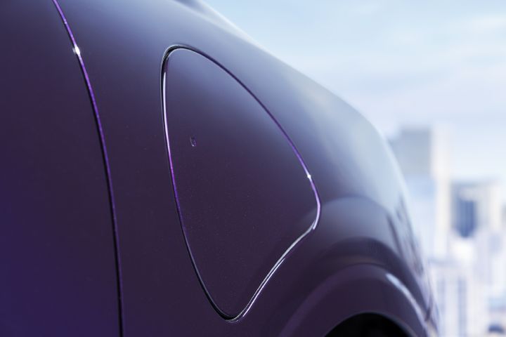 Nærbilde av Nissan PIXO ladeport integrert i bakre kvartpanel, ferdigstilt med metallisk lilla lakk.