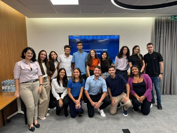 Grupo de estagiário de São Paulo em uma sala de reuniões sob o carpete de costas para uma televisão