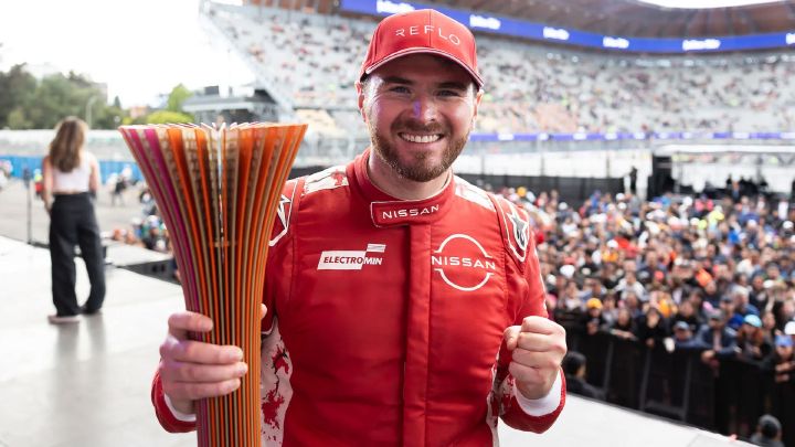 Oliver Rowland comemora no pódio segurando o troféu em uma mão e um espumante na outra enquanto confetes caem ao seu redor