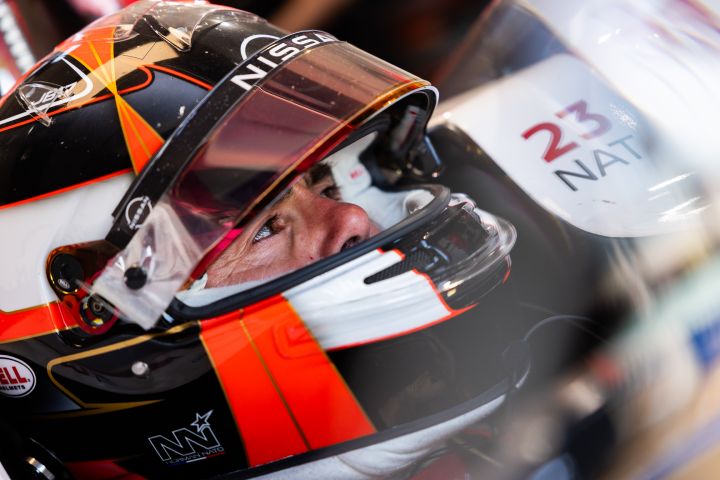 Norman Nato sitzt mit seinem schwarzen Helm auf dem Kopf und hochgeklapptem Visier im Auto mit der Nummer 23 in der Nissan Teamgarage.