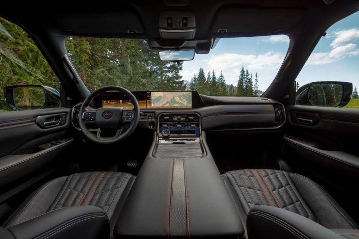 The black dashboard, center console, and windshield from the view of the rear passenger seats in a 2025 Nissan Armada.