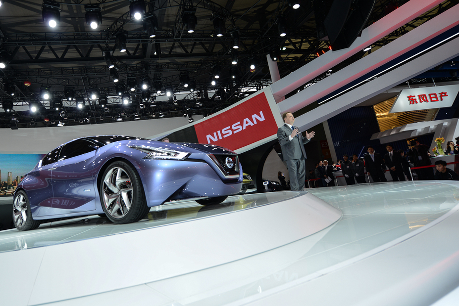 a man speaking next to Nissan vehicle on a stage