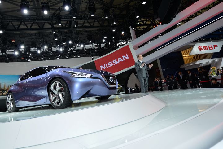 a man speaking next to Nissan vehicle on a stage