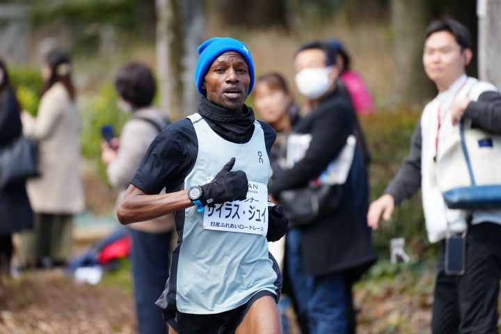 サイラス・ジュイさんが黒いTシャツ、青い帽子を身に着けて日産テクニカルセンター内を走っている様子