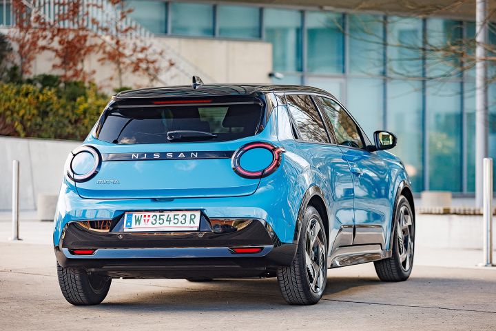 Blick von schräg hinten auf einen leuchtend blauen Nissan Micra mit schwarzem Kontrastdach