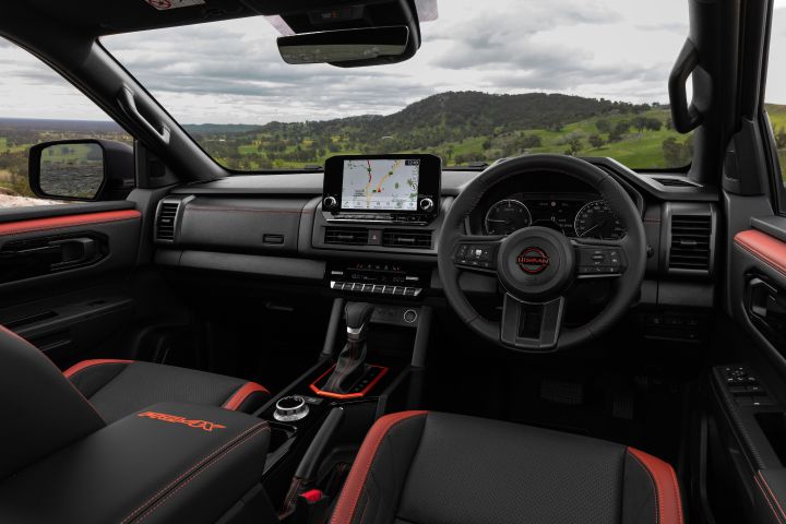 2026 Nissan Navara PRO-4X finished in Boulder Grey presented in a cockpit-wide interior shot with both front seats and dashboard visible.