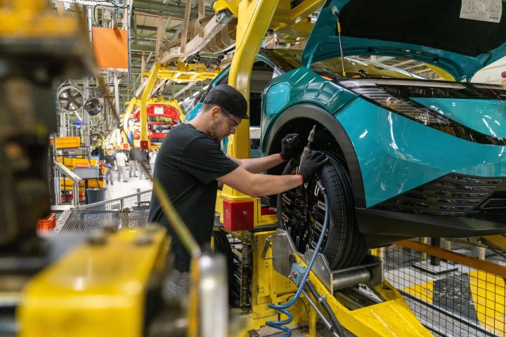 Ein Mitarbeiter montiert ein Rad an einem Nissan LEAF im Nissan Werk Sunderland