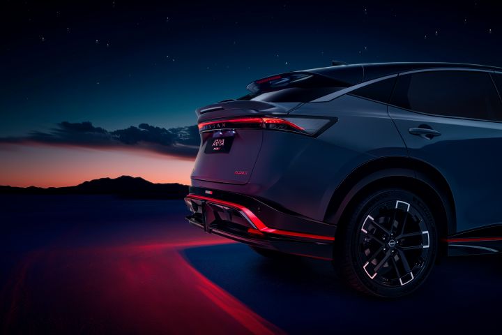 Static ¾ angle shot of the rear of the Ariya NISMO with the red tail lights illuminated