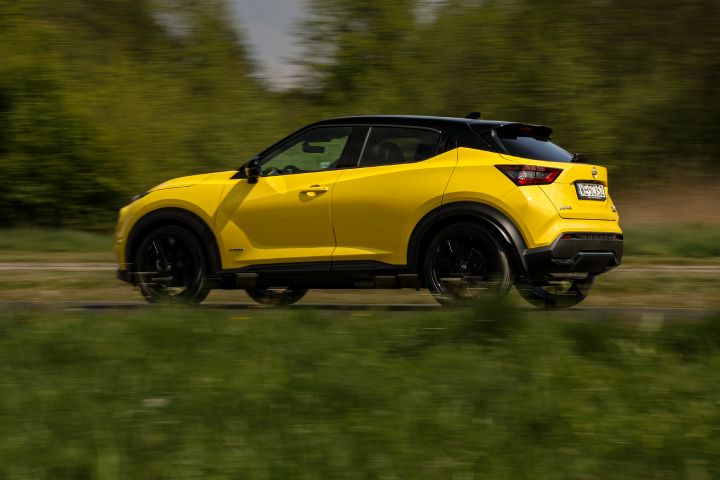 Jadący żółty Nissan Juke (widok z boku) na tle zieleni