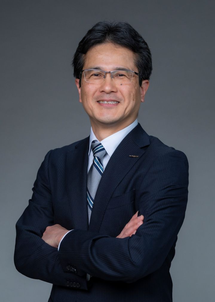 Portrait of Teiji Hirata with his arms folded (suit, tie and NISSAN corporate pin) (smiling)