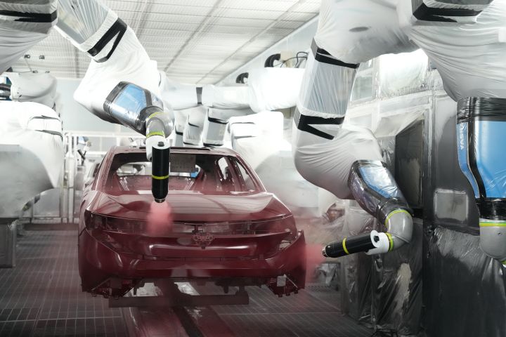 栃木工場の塗装工程で、ロボットアームがリーフの車体に赤色の塗料を均一に吹き付けている様子
