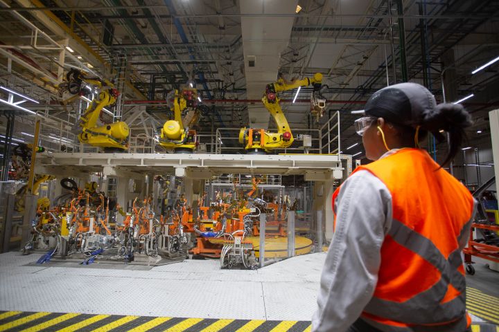 Funcionário da linha de montagem da Nissan em Resende olha para um dos novos robôs de produção do complexo