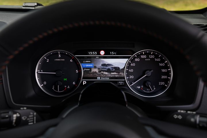 2026 Nissan Navara PRO-4X finished in Boulder Grey showing the instrument binnacle with GRAVEL off-road mode, analogue dials and drivetrain range indicators.