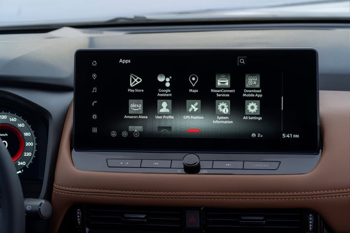 Der Touchscreen des Infotainment-Systems im Nissan X‑Trail Tekna zeigt ein App-Menü mit Symbolen für Play Store, Google Assistant, Maps, NissanConnect Services, Amazon Alexa, Benutzerprofil, GPS-Position, Systeminformationen und Alle Einstellungen. Der Bildschirm hat einen schwarzen Hintergrund mit weißen Symbolen und weißem Text, ein Suchsymbol in der oberen rechten Ecke und die Uhrzeit 17:41 Uhr in der unteren rechten Ecke.
