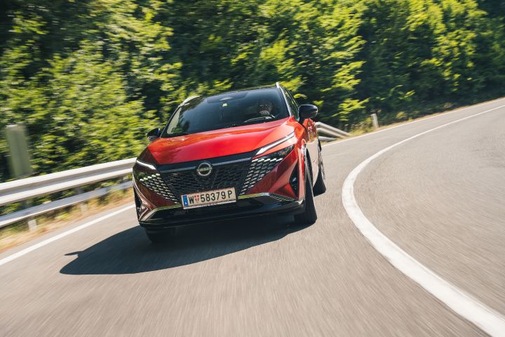 Ein Nissan Qashqai in Fuji Sunset Red fährt durch eine Kurve, Frontalansicht