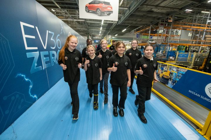 A group of schoolchildren walking at the Nissan Sunderland Plant, with an EV36Zero branding in the background