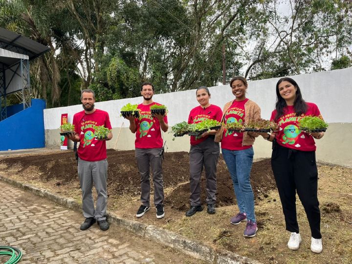 Integrantes do projeto Escola Verde da Nissan segura pés de alface da primeira colheita